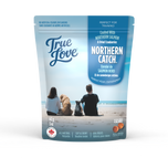 Bag of True Love dog treats with a family and their dogs on an ocean beach. Northern Catch flavour - northern salmon and dried cranberries.